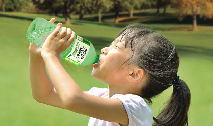 A girl drinking a bottle of Ice River Green Bottle Water.