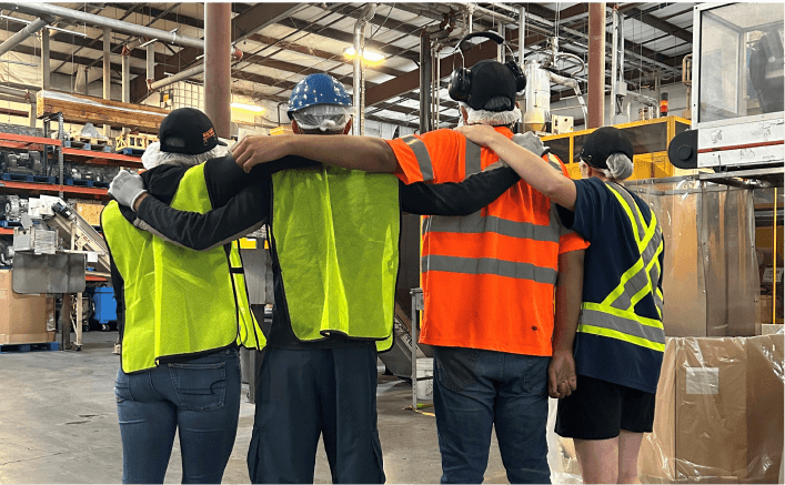 Four staff members standing with their arms around each other.